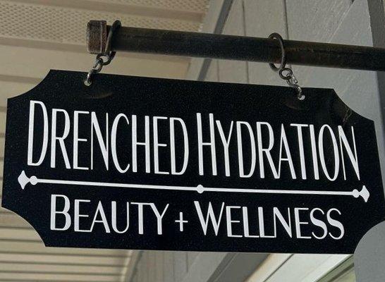 Drenched Hydration Beauty + Wellness hanging sign with brand logo
